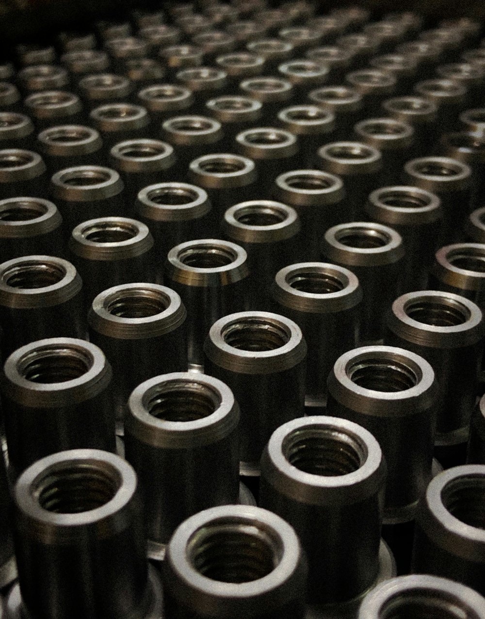 Rows of identical machined metal parts standing on a table